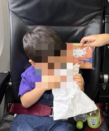 往路の機内でおしぼりを受け取る様子(モザイク処理済み)