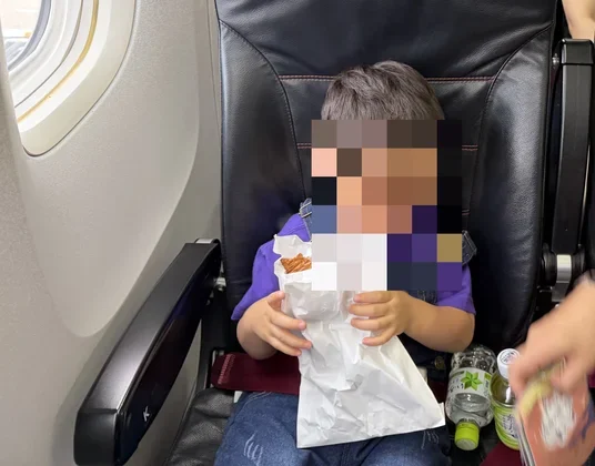 往路の機内でおやつを食べる様子(モザイク処理済み)