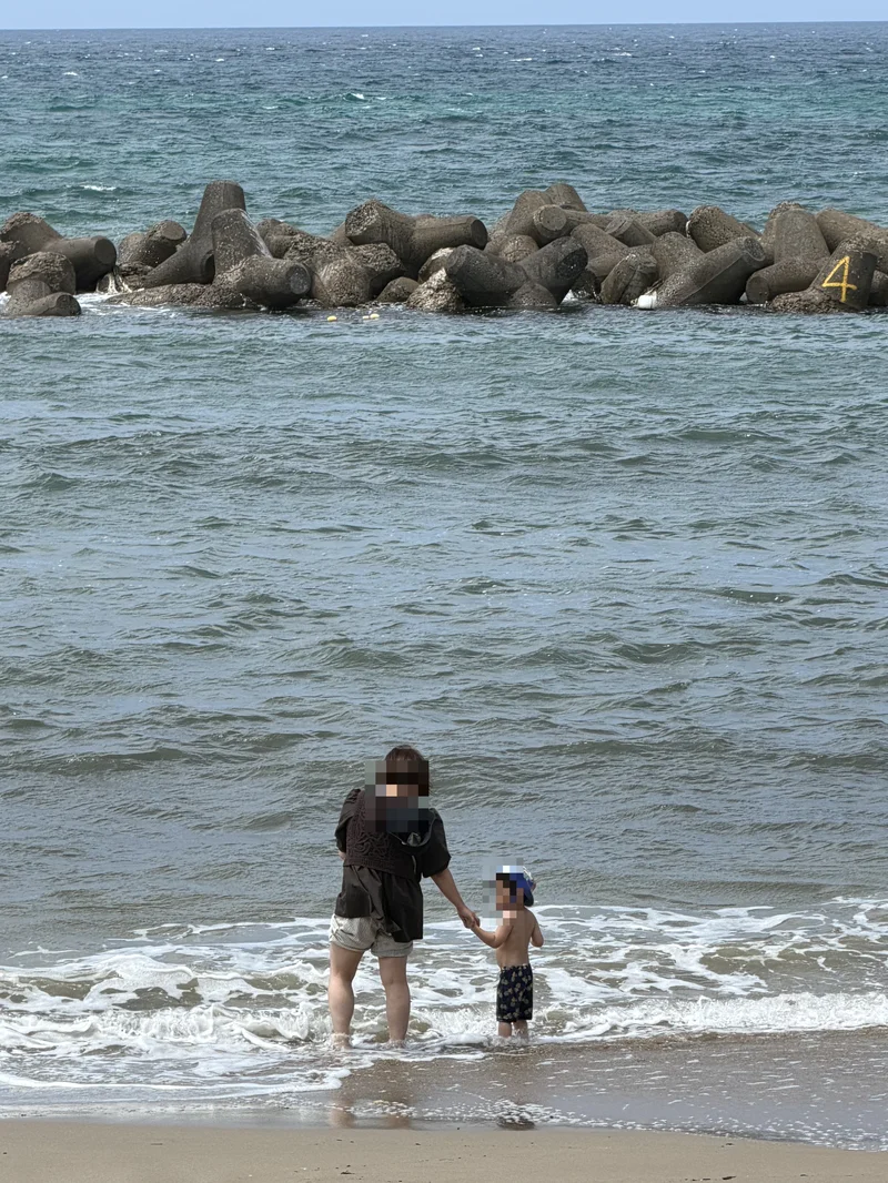 海に入って手をつなぐ大人と子ども