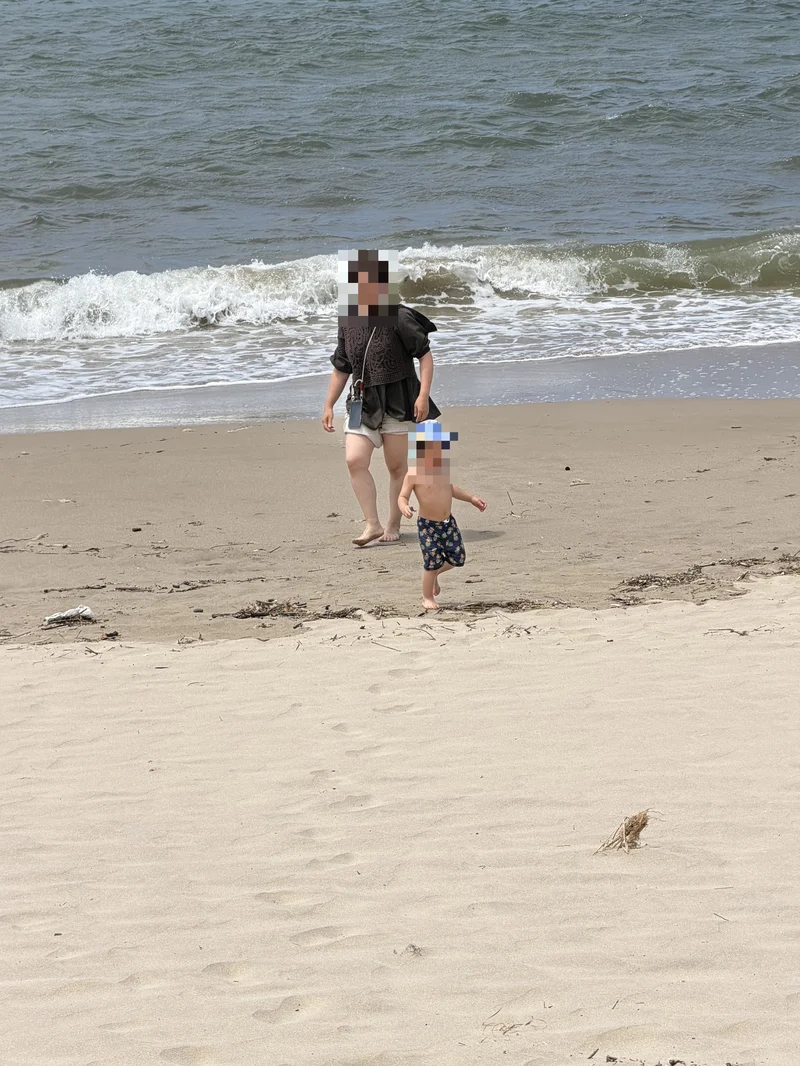 砂浜を走る子どもと歩く大人